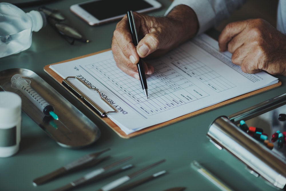 Clipboard being written on by doctor