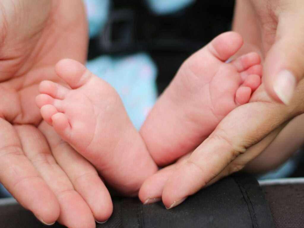 A parent holding their baby's feet