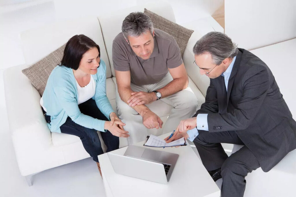 An advisor talking to a couple. He shows them a spreadsheet